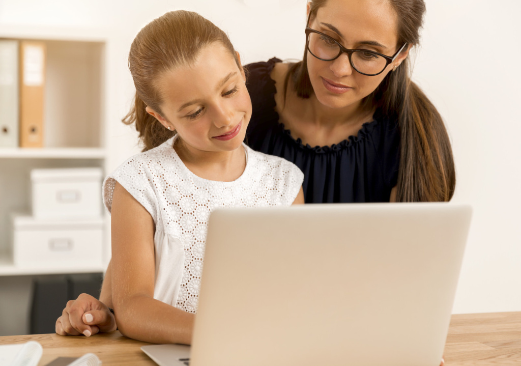 Learn more about how to choose a homeschool curriculum. Mom is teaching her daughter to study for homeschool.